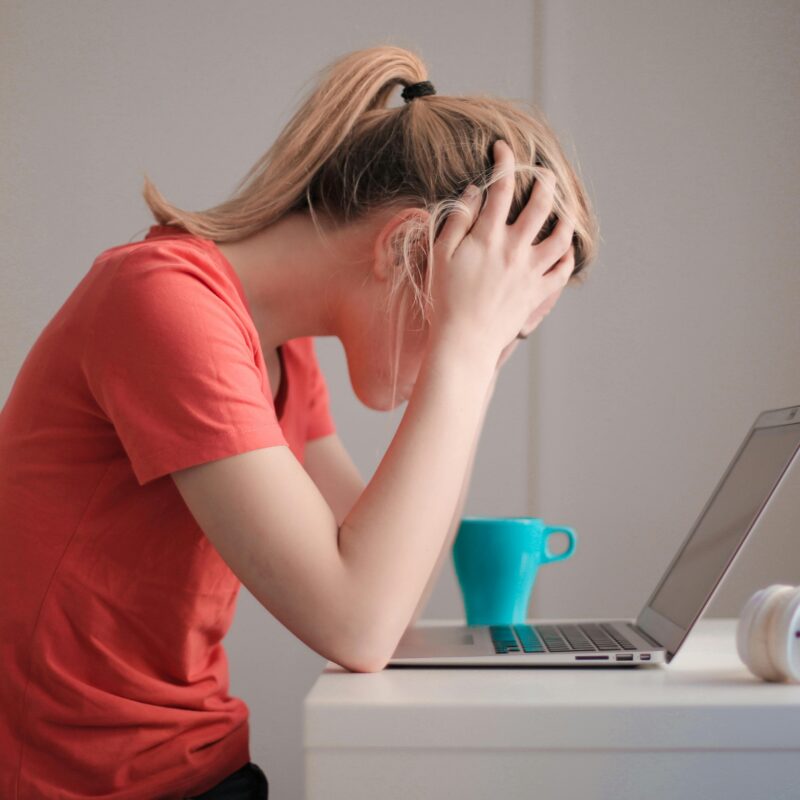 woman sitting at her desk looking stressed out with her computer and a cup of coffee